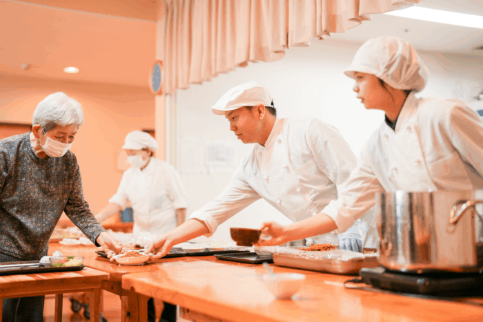 入居者と職員が一緒に調理・食事準備をしている風景。レクリエーション活動の様子。